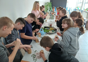 Uczniowie przygotowują doniczki do sadzenia roślin.