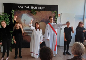 uczniowie prezentują wielkanocną pantomimę, w tle Grób Pański i napis "Bóg dał nam ręce"